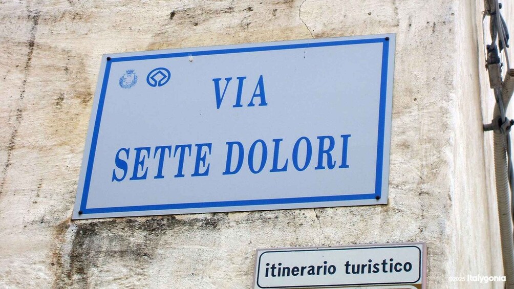 Un letrero que indica 'VIA SETTE DOLORI', señalando una ruta o dirección. 5