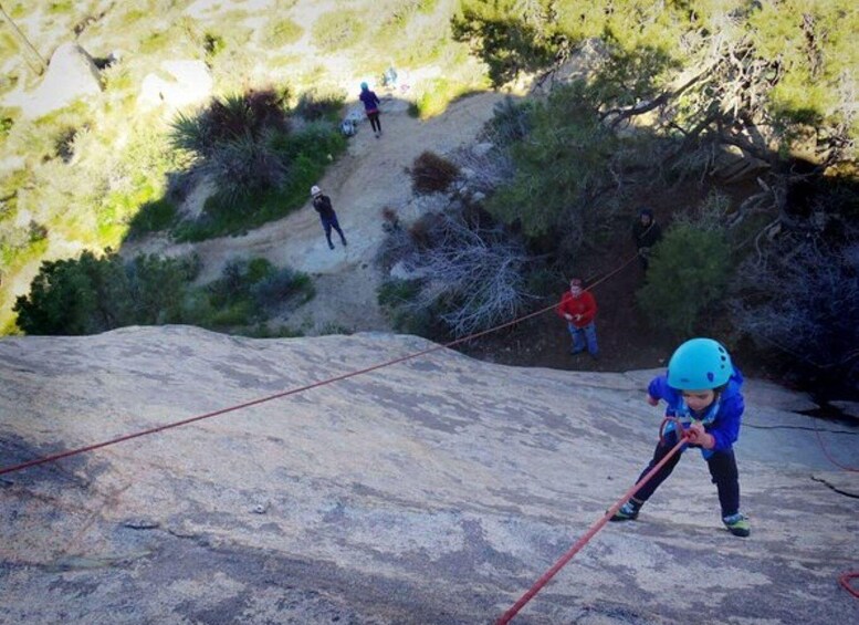 A person rappelling down a rocky slope with a rope. 5