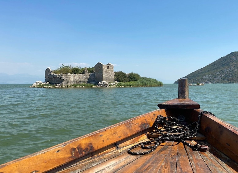 A wooden boat with a rope and a stone castle on an island in the water. 3