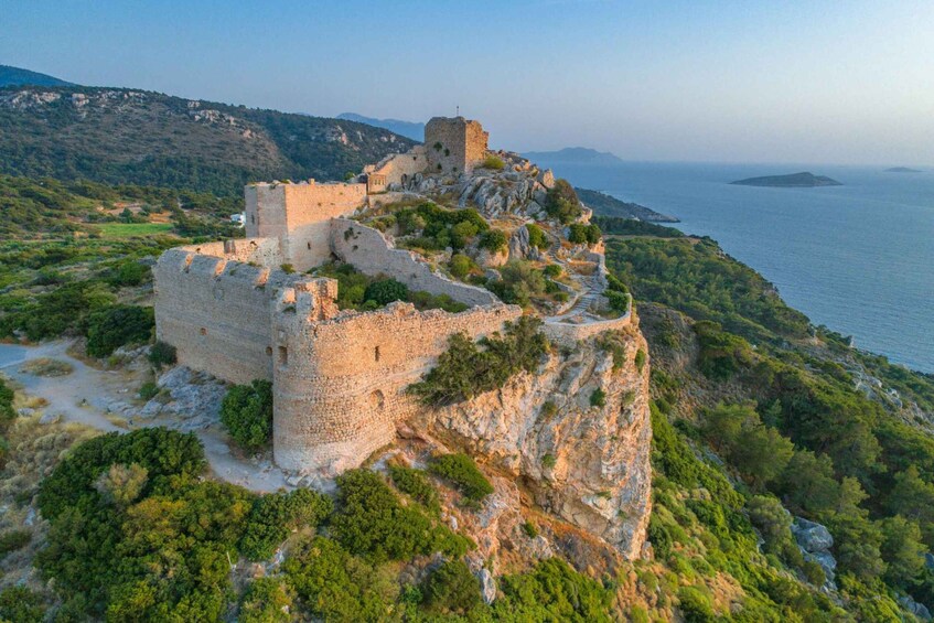 An ancient stone fortress on a cliff overlooking a coastal area. 1