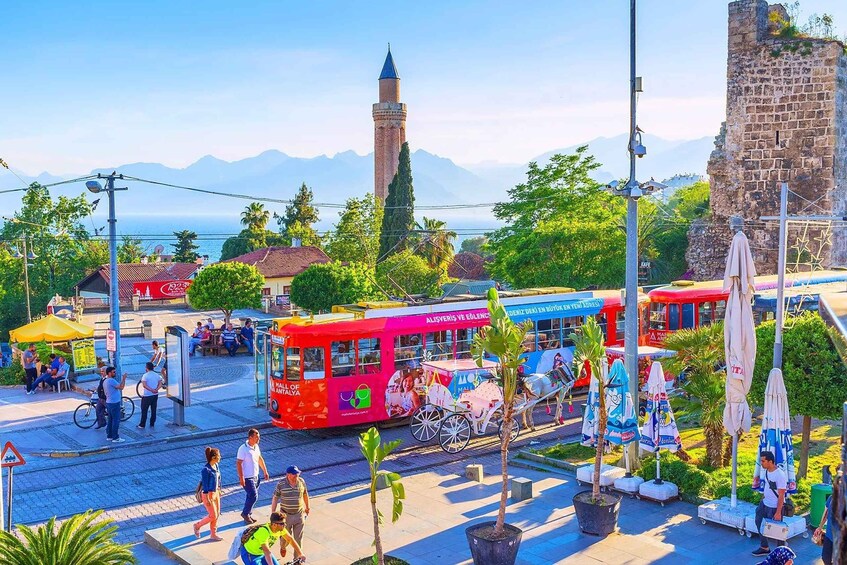 A vibrant street scene with a red tram, pedestrians, and a historic tower. 5