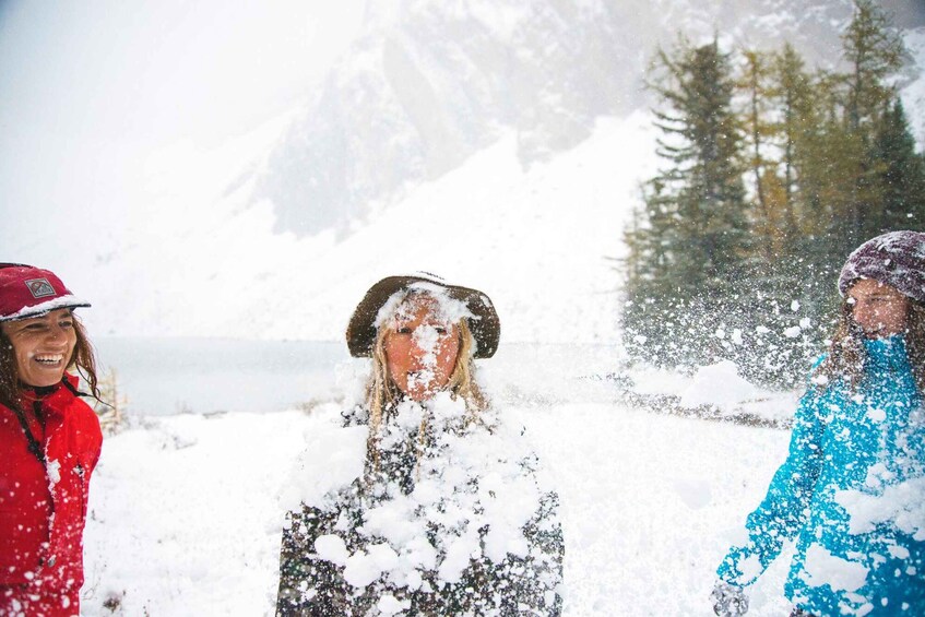 Three people in a snowy landscape with mountains in the background. 3