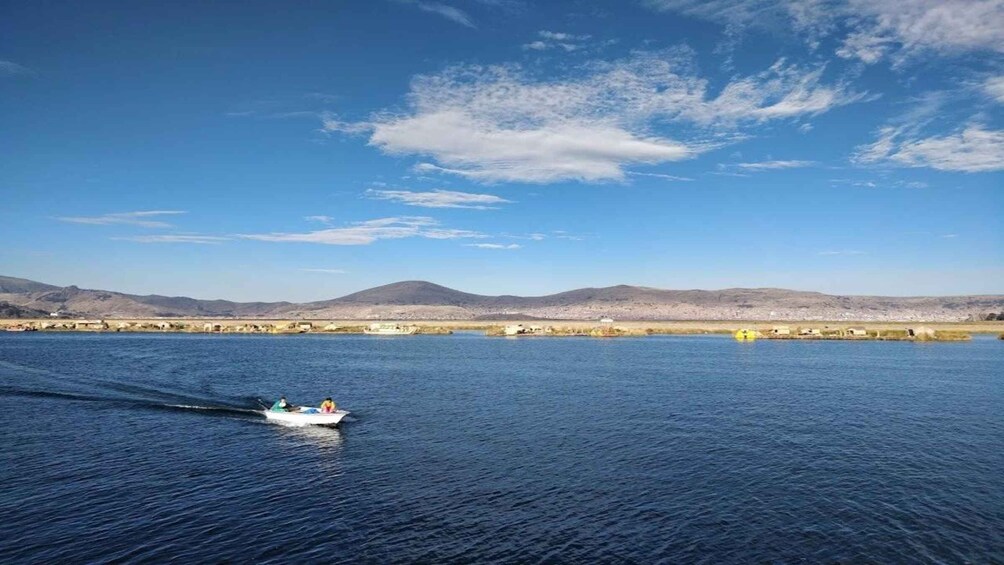 A boat on a calm body of water with mountains in the background. 2