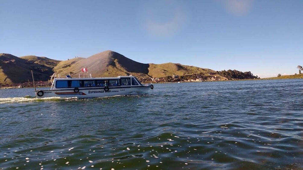 A boat named 'Esperanza Hiva Express' on a body of water with hills in the background. 4