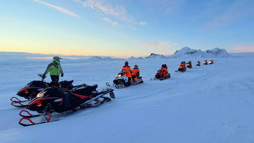 A group of snowmobiles on a snowy landscape with a clear sky. 2