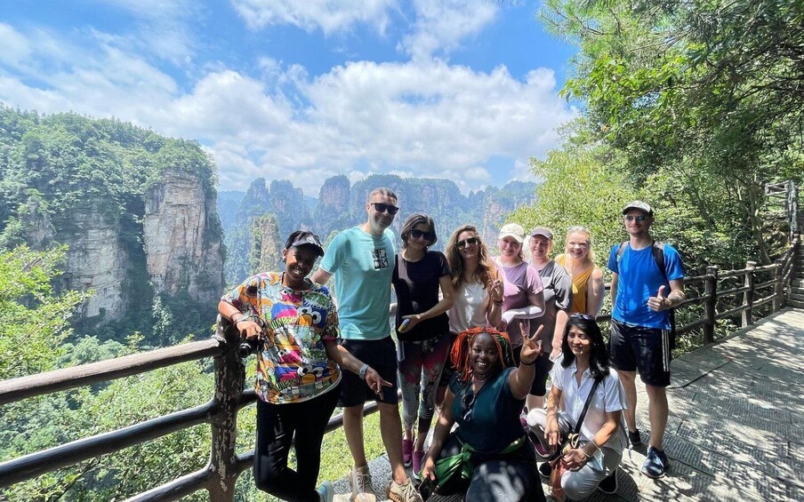 A group of people on a bridge with a scenic view of rock formations and greenery. 2