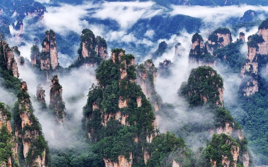 Towering limestone peaks, lush greenery, and misty clouds. 1