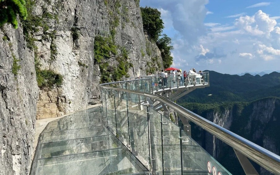 A glass bridge with a glass walkway extending over a canyon. 4