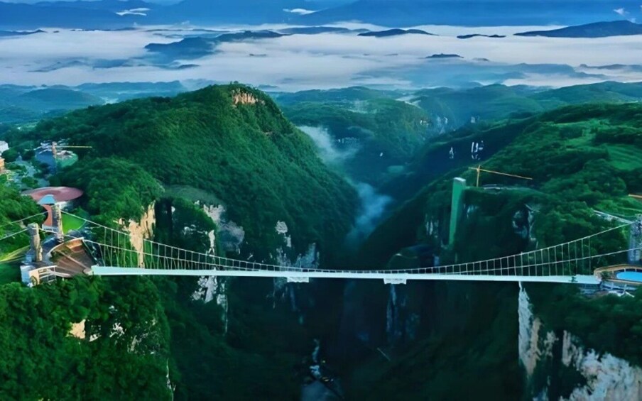 A suspension bridge over a deep gorge with lush greenery and waterfalls. 3