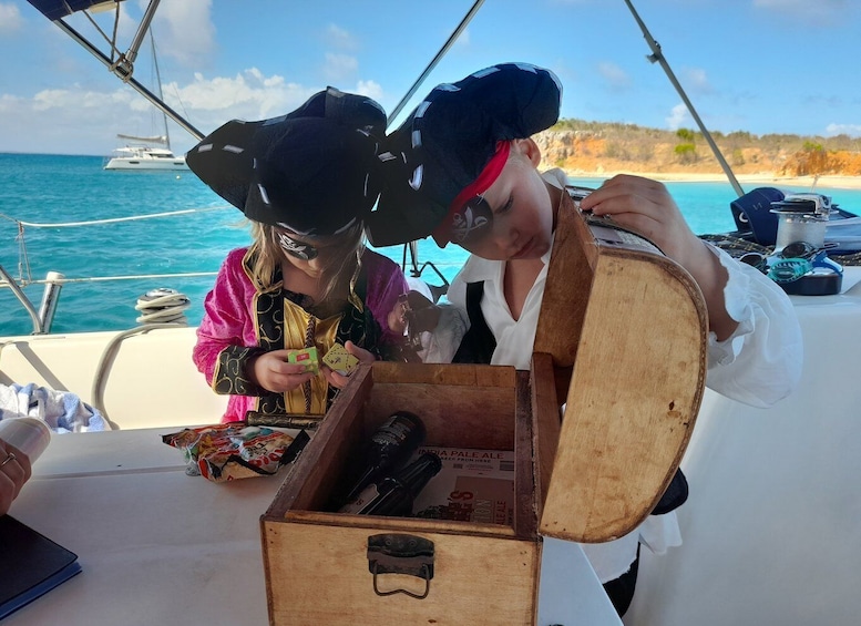 Two people on a boat, one holding a wooden chest with a bottle of beer and playing cards. 5