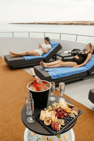 A lounge area with reclining chairs, a tray of fruit and a bottle of champagne. 2