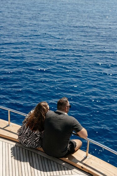 Two people sitting on a boat deck overlooking the ocean. 5