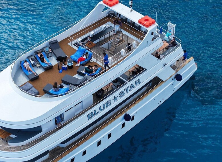 A large, modern cruise ship with multiple decks and a spacious outdoor lounge area. 1