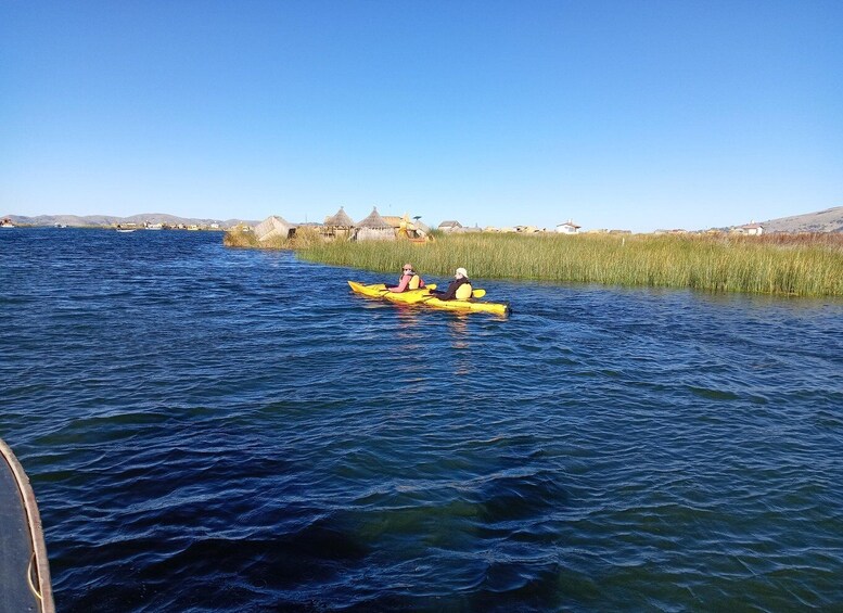 A person kayaking on a calm body of water with houses and vegetation in the background. 5