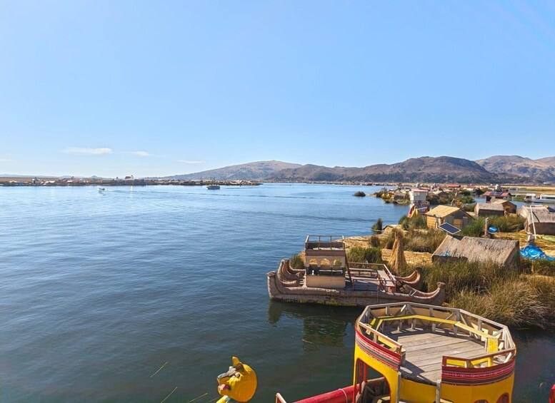 A calm lake with boats, a yellow boat docked on the shore, and a mountainous landscape in the distance. 2
