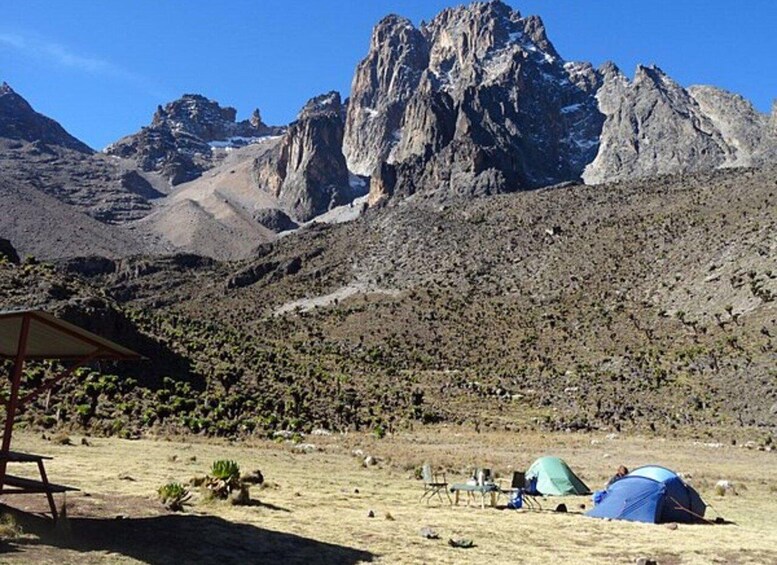 A mountainous landscape with tents and a picnic table. 1
