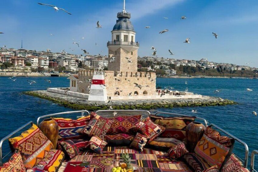 A boat with colorful cushions, a lighthouse, and seagulls flying over the water. 1