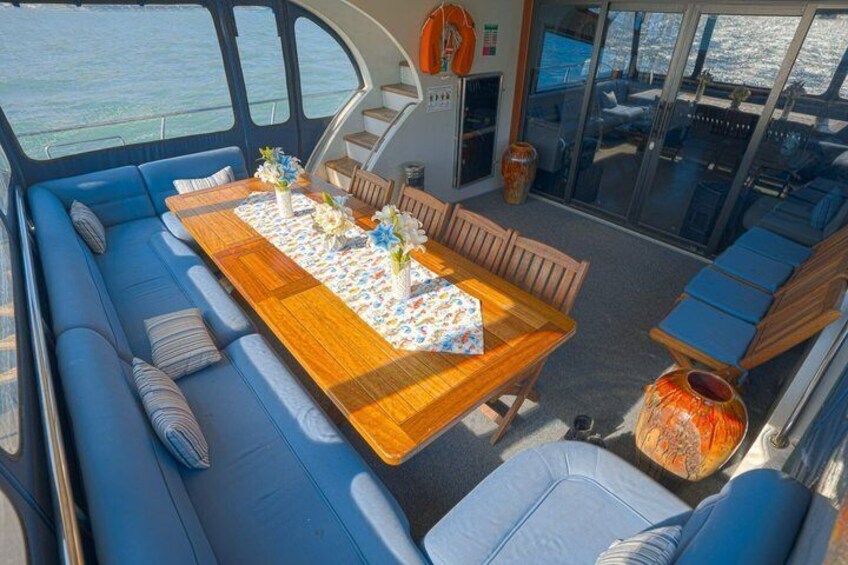 A boat interior with a dining table, blue seating, and a glass door leading to an outdoor area. 3