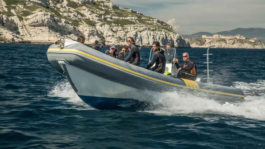 A speedboat with passengers, moving through a coastal area with rocky cliffs and a building in the background. 3