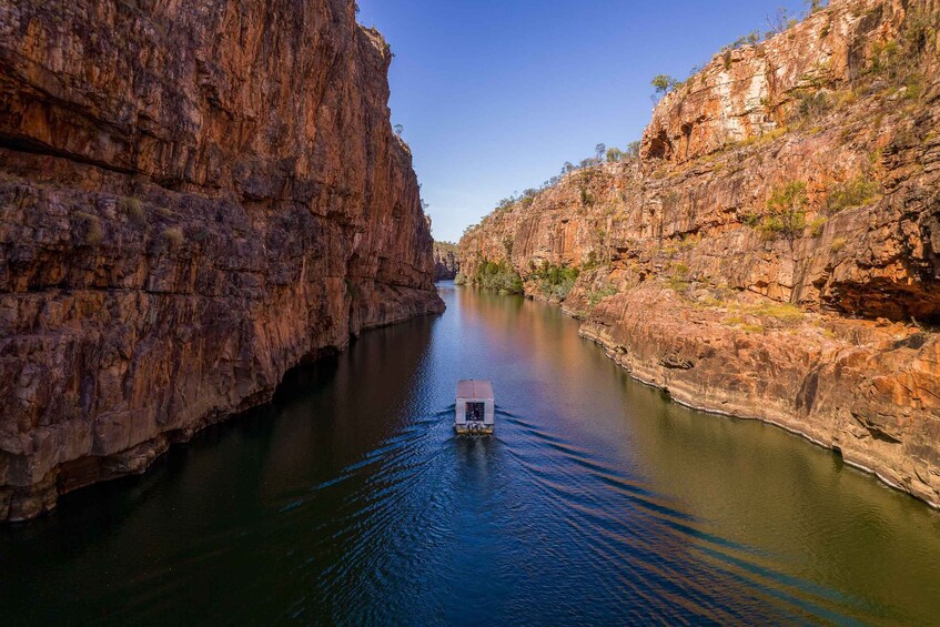 A narrow canyon with steep cliffs and a boat navigating the waterway. 2