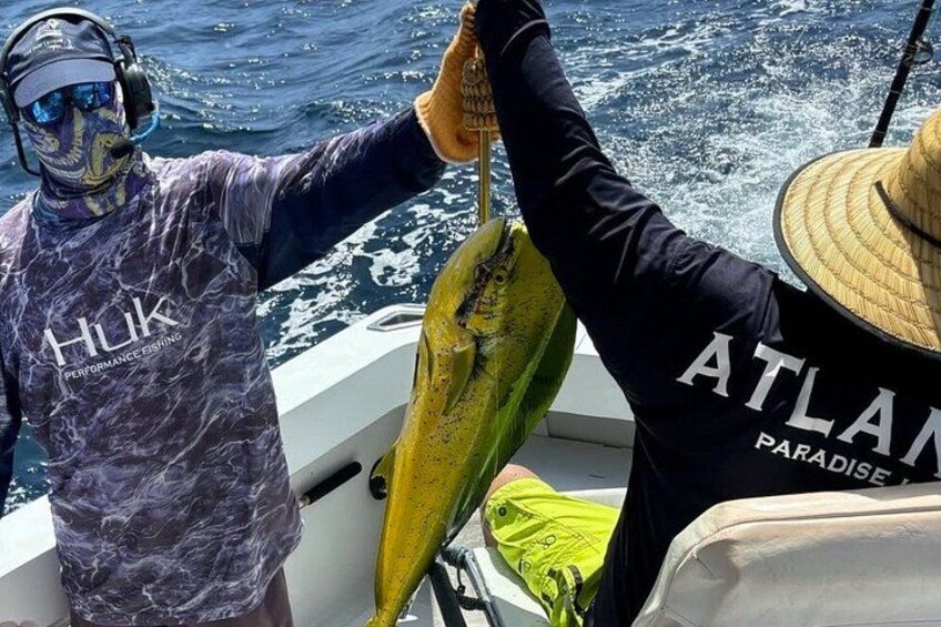 Een persoon in een 'Hulk' shirt houdt een vis vast op een boot. 2