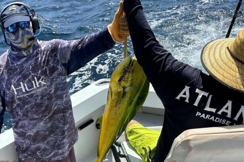 Une personne portant un t-shirt à l’effigie de « Hulk » et tenant un poisson sur un bateau. 2