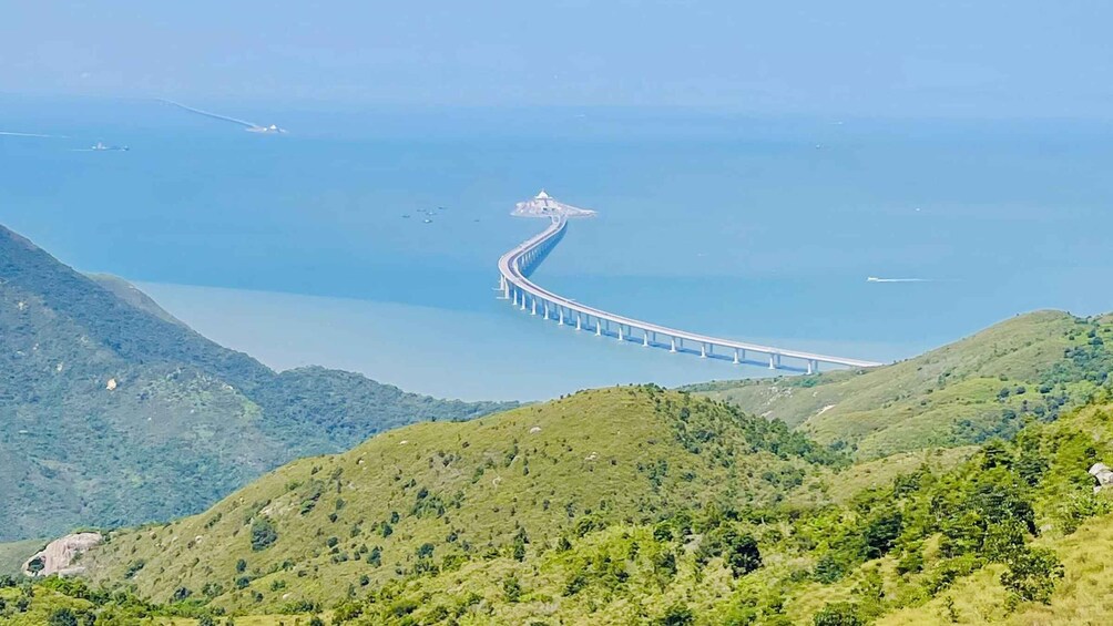 A long bridge curving over a body of water, surrounded by green hills. 4