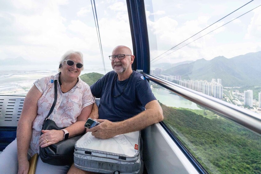 Two people on a cable car with a city and mountains in the background. 2