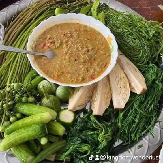 A bowl of soup surrounded by fresh vegetables like cucumbers, leafy greens, and herbs. 3