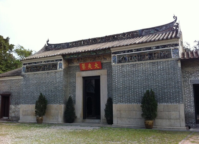 A traditional building with a tiled roof, brick walls, and a red sign. 1