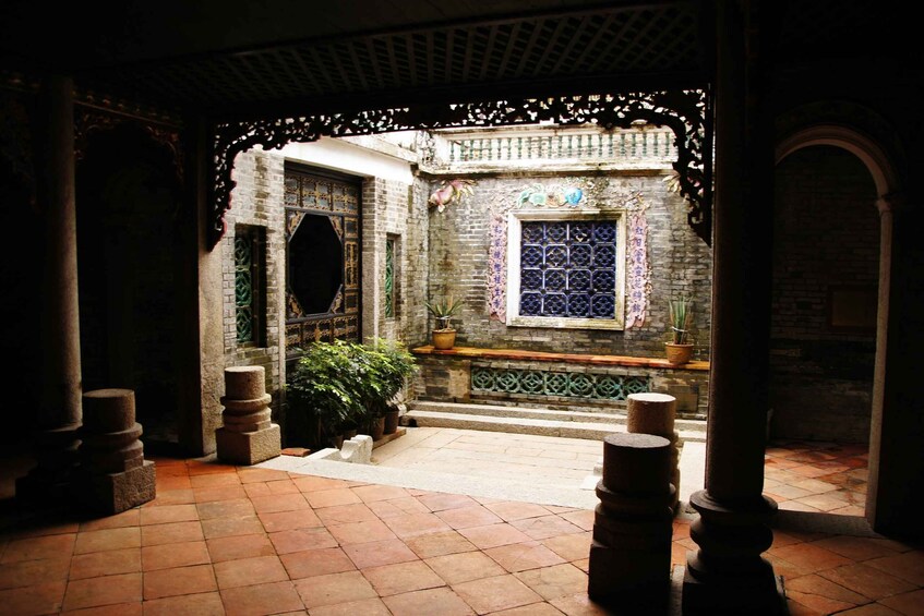 An interior courtyard with a tiled floor, a window with blue patterned glass, and decorative brickwork. 2