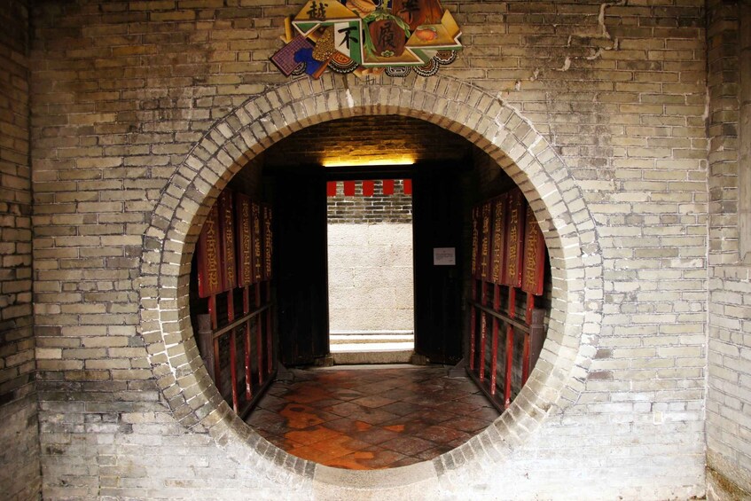 An arched brick entrance with traditional Chinese decorations and a tiled floor. 3