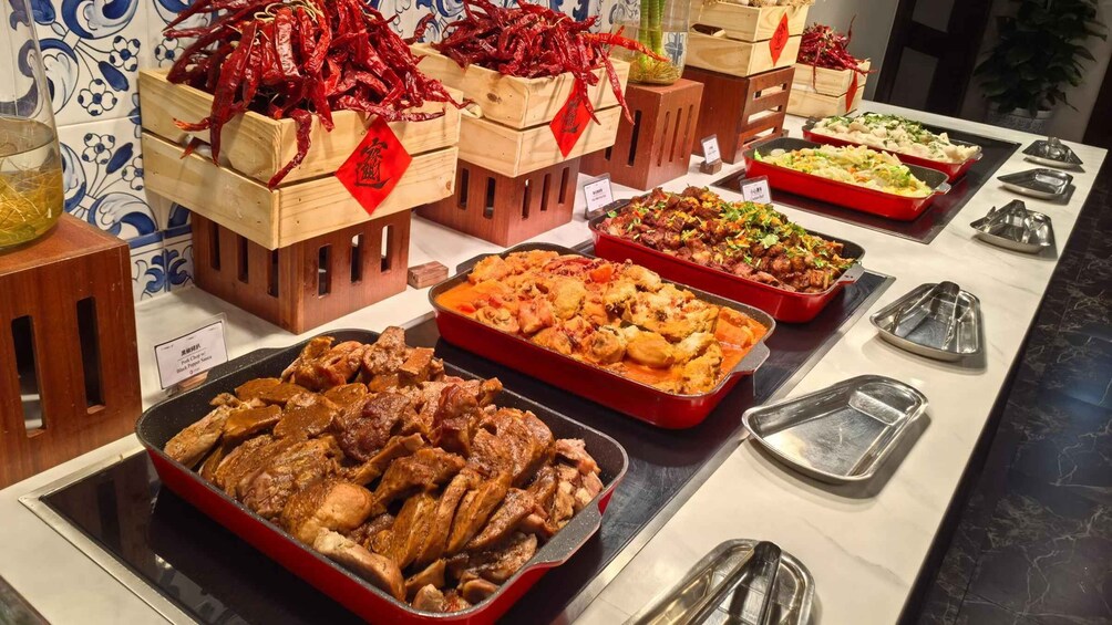 A buffet with various dishes, including a tray of roasted chicken, a red casserole, and a salad. 3
