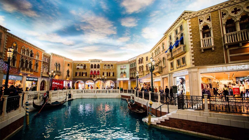 A Venetian-style indoor canal with gondolas, shops, and a clear sky. 2