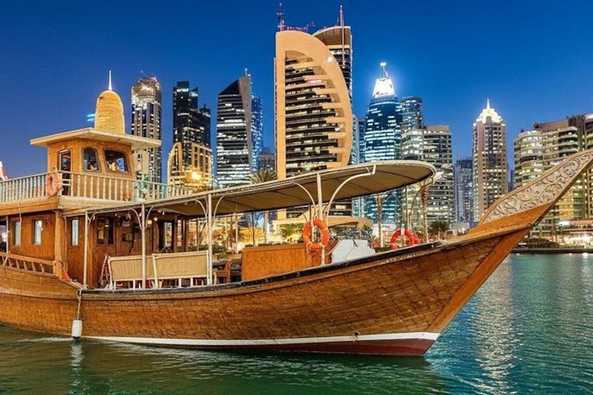 A traditional wooden boat with a canopy, docked in a body of water with a city skyline in the background. 4
