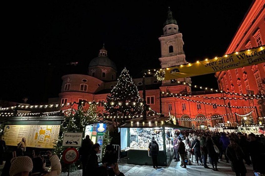 A festive market square at night with illuminated buildings and a large Christmas tree. 4