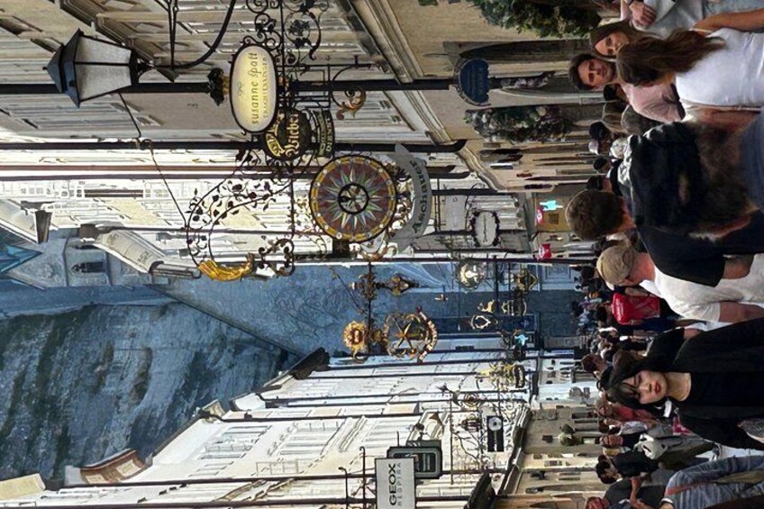 A street with people, a large blue structure, and a clock tower. 2