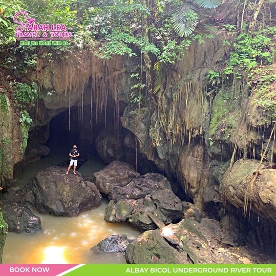 A person standing on rocks in a cave with water flowing through it. 3