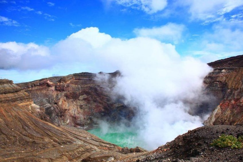A volcanic crater with steam and a green pool of water. 4