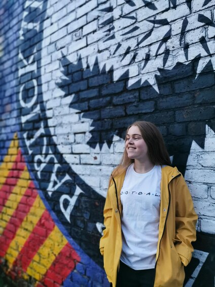A person standing in front of a graffiti-covered brick wall. 5