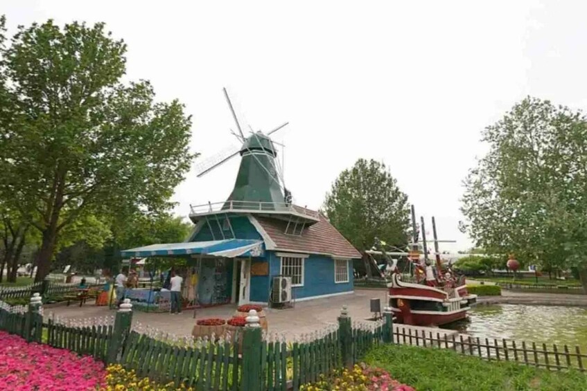 A windmill, a small blue building, and a boat on a canal. 4