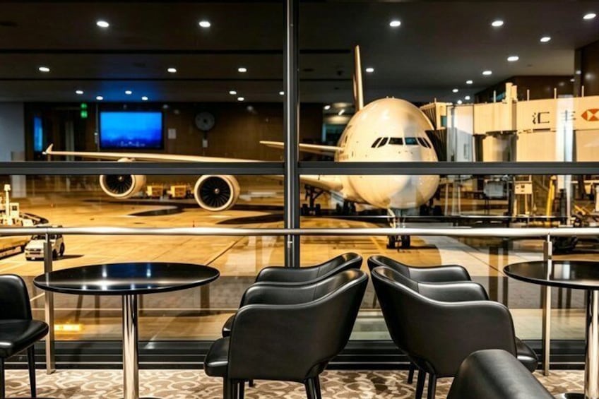 An airplane parked at an airport terminal with seating areas in the foreground. 5
