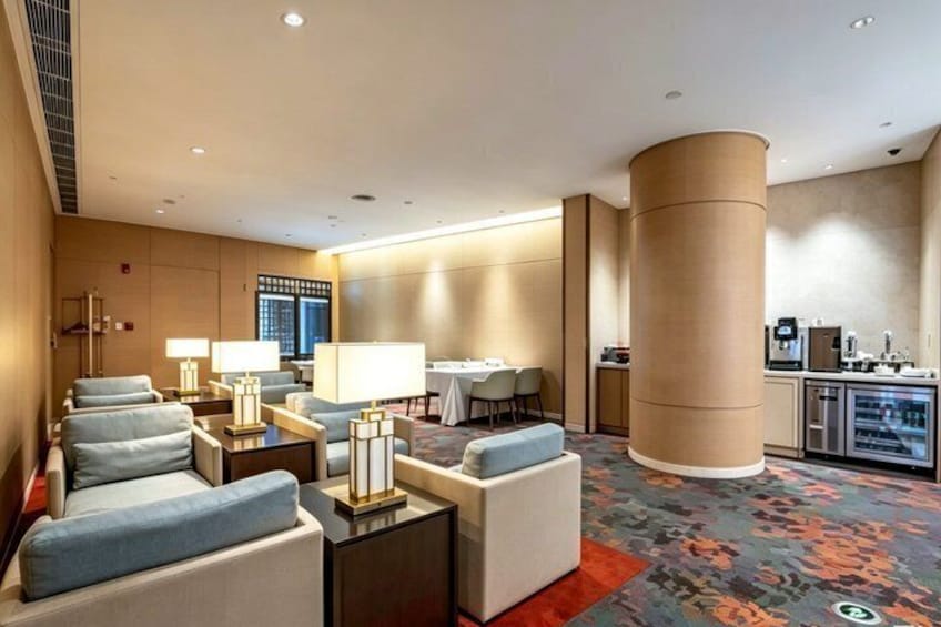 A hotel lobby with seating, a coffee station, and a large pillar. 1