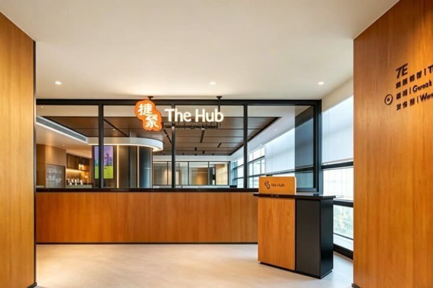 A modern interior with wooden accents, a reception desk labeled 'The Hub,' and a sign with Chinese characters. 4