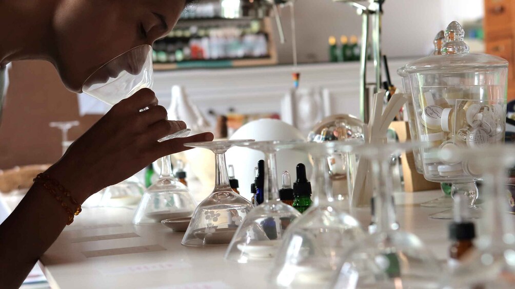 A person examining a clear glass container with a liquid. 1