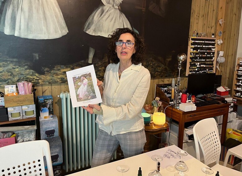 A person holding a framed picture in a room with wooden walls, a radiator, and shelves with various items. 5