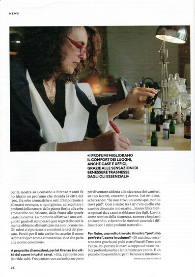 A person writing in a notebook at a table with various bottles and a lamp. 3