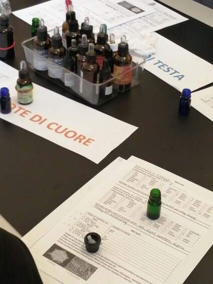 A table with various essential oils, a document titled 'TESTA,' and a bottle labeled 'VANILLE.' 4