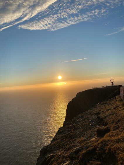 A sunset over a coastal cliff with a spherical structure on top. 2