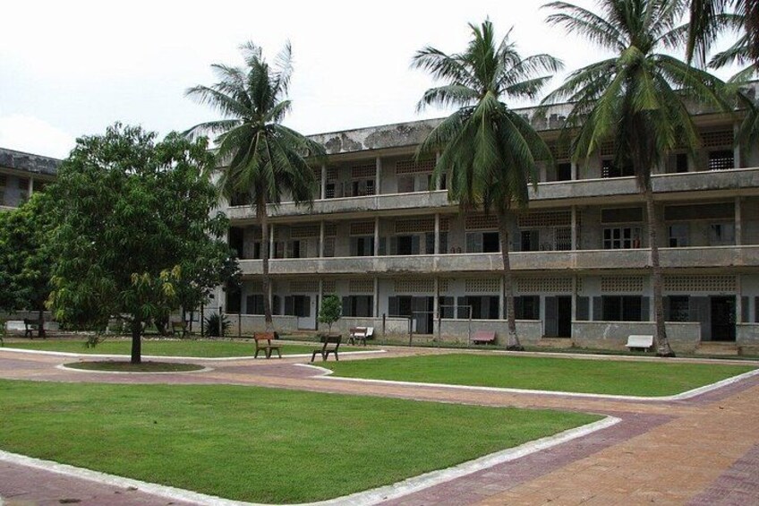 A multi-story building with a lawn in front, palm trees, and benches. 5